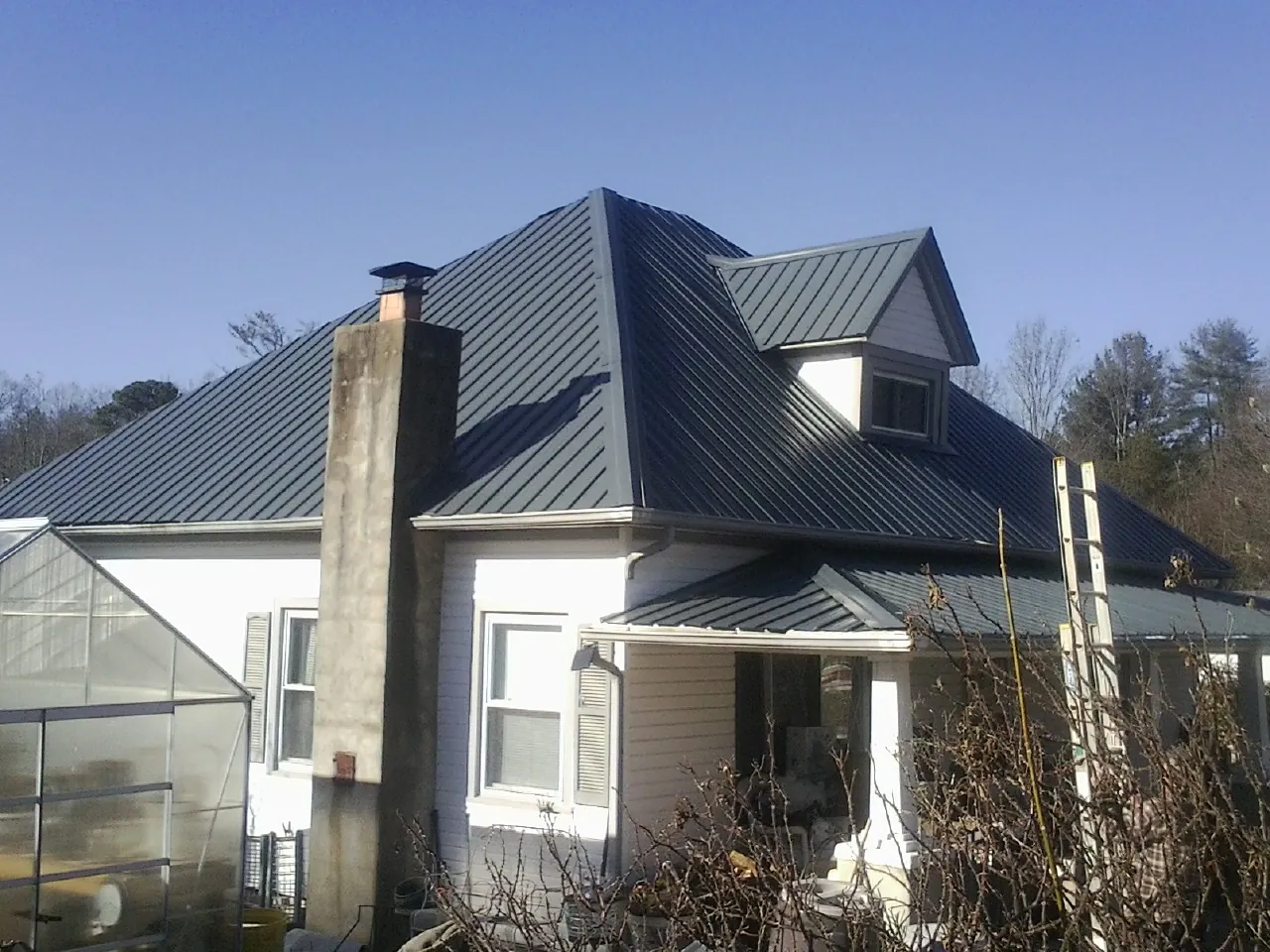 Dark blue standing seam metal roof on a white farmhouse with dormer — Slate & Tile Roof Repair by Roofing Brothers in Hanover