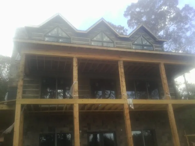 Dormers and porch framing on a large log home under construction — Roof Coating work by our crew in Hanover